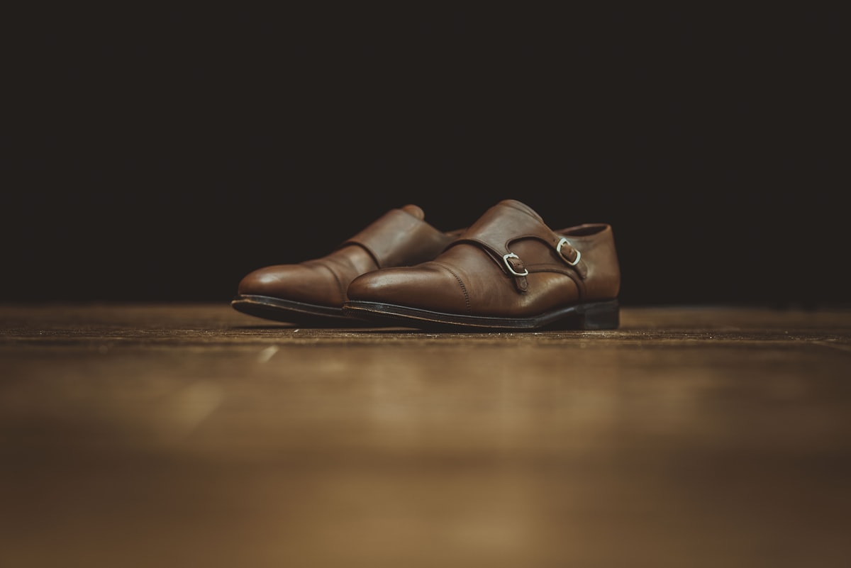 Sapatos de couro sobre madeira escura, interior em penumbra